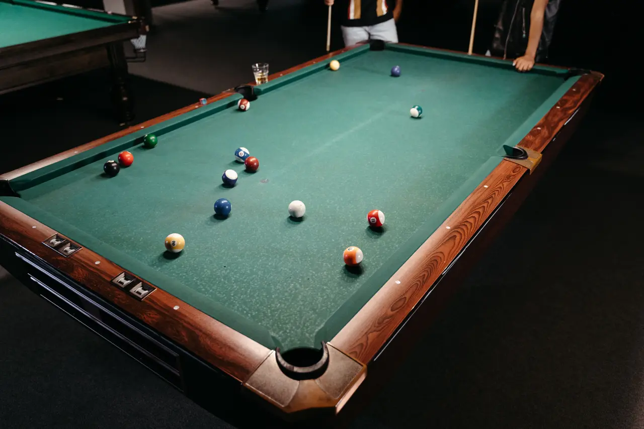 Table de billard en cours de partie, deux joueurs queue en main dans une salle de jeux