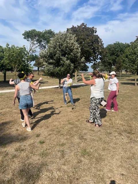 Collègues formant un cercle et manœuvrant ensemble un dispositif à élastiques lors d'un défi coopératif MyBestCoaching en plein air