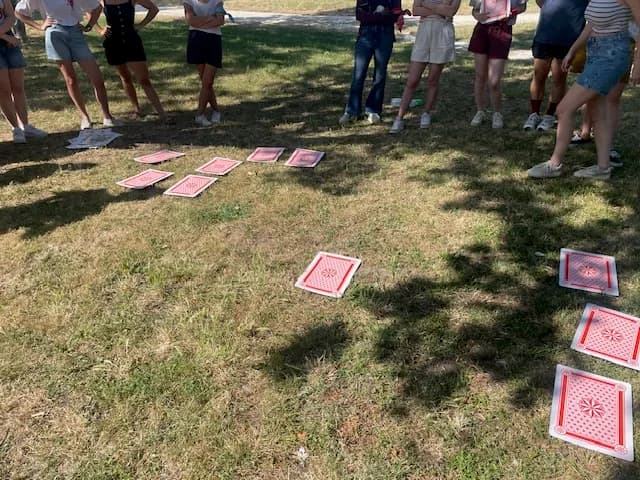 Équipe rassemblée autour d'un jeu de cartes géantes posées sur la pelouse d'un parc pendant un atelier de cohésion MyBestCoaching