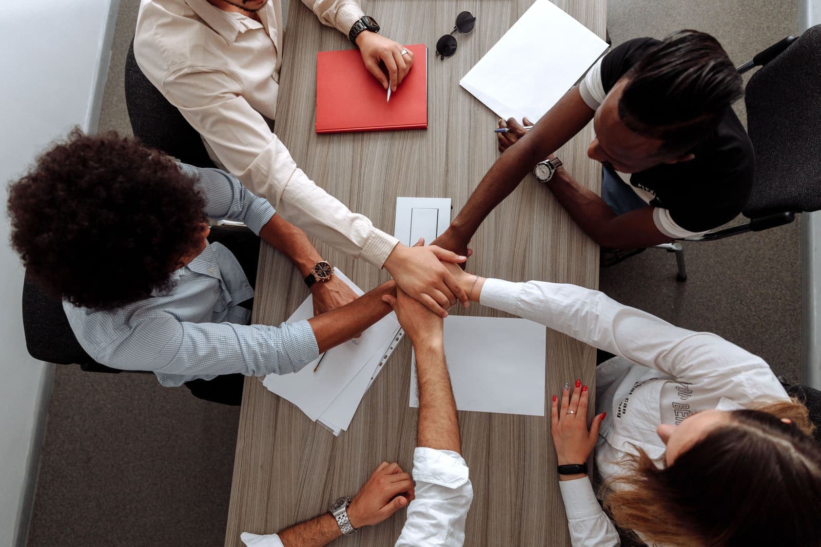 Collaborateurs d'une entreprise à Angers se donnant la main autour d'une table de réunion, cohésion d'équipe et confiance mutuelle lors d'un programme de team building sportif MyBestCoaching
