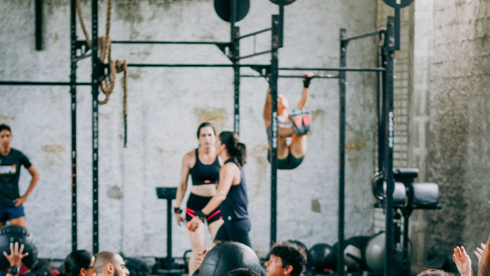 Athlètes en plein WOD dans une box de CrossFit, tractions sur barre et exercices au poids du corps