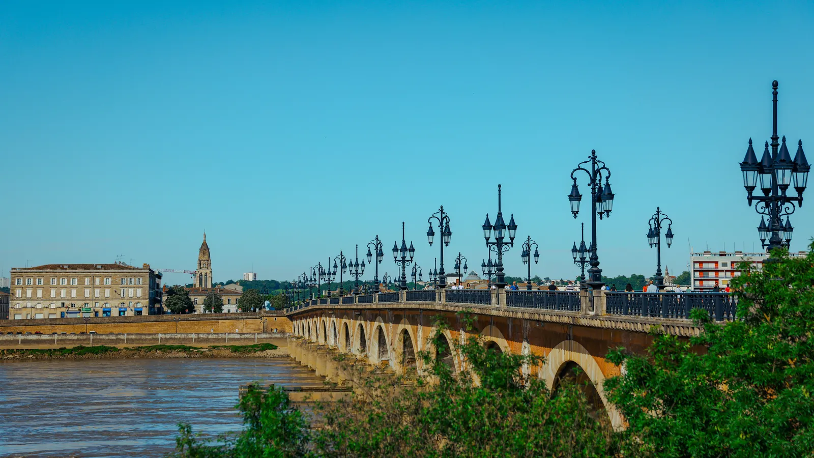 Le Pont de Pierre et les quais de la Garonne à Bordeaux, sous un ciel bleu dégagé